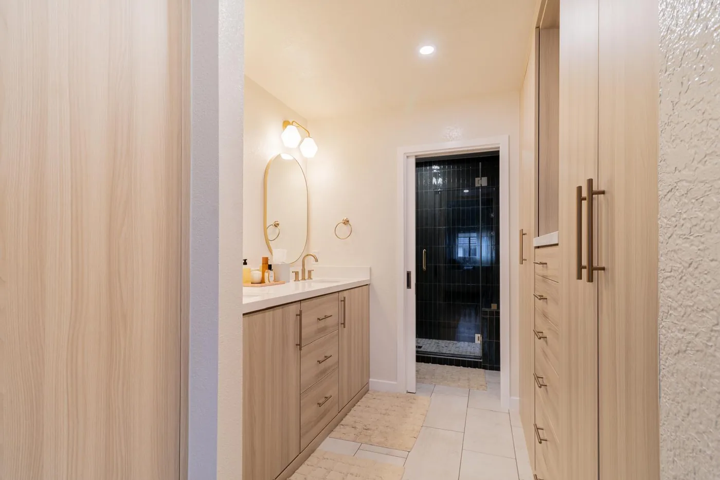 Light oak vanity run with dark tile wet room